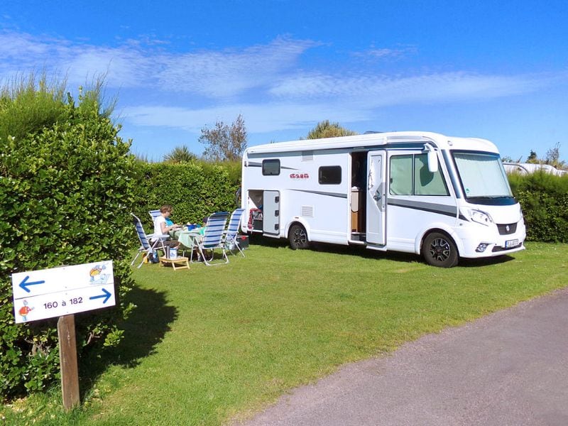 Camper met vrouw op tuinset ervoor.