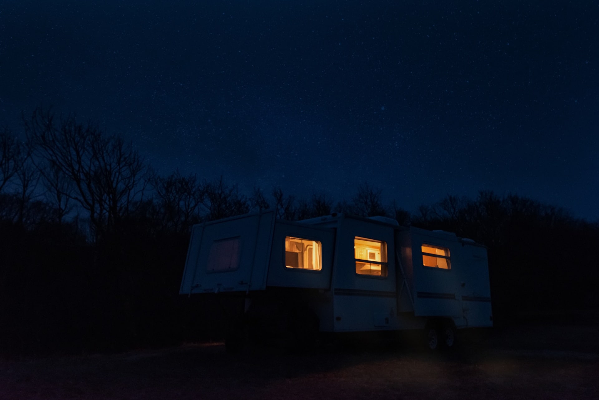 Heel gezellig, met zijn allen kamperen in de sneeuw! Een caravan met een donkere avondlucht zonder vuurwerk