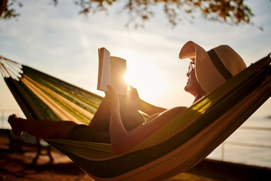 vrouw leest boek in hangmat