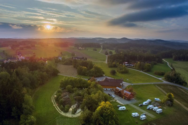 Luchtfoto van Camping Waldviertel bij zonsondergang, met kampeerplaatsen, glooiend landschap en bossen in Oostenrijk