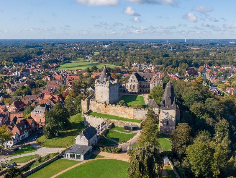 Luchtfoto van kasteel Bad Bentheim, omringd door groene heuvels en het dorp met rode daken in de Duitse regio Nedersaksen.