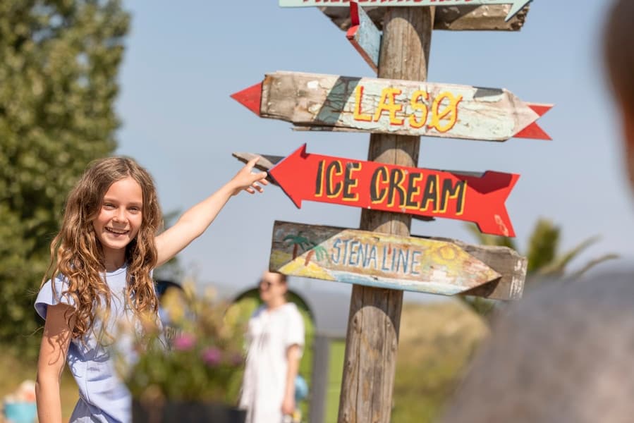 meisje wijst naar wegwijsborden op het strand
